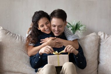 Sevgi dolu kız arkadaş sevgilisini kutluyor, arkadan sarılıyor, hediyesini sunuyor.