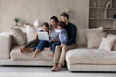 Çocuklu mutlu ebeveynler bilgisayar kullanıyor, internette eğleniyorlar.