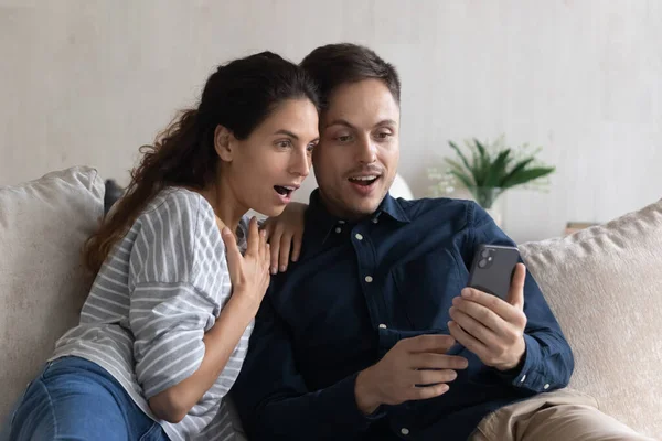 Έκπληκτο ζευγάρι κοιτάζοντας οθόνη smartphone, διαβάζοντας απρόσμενες ειδήσεις — Φωτογραφία Αρχείου