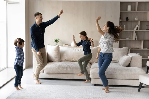 Glückliche Familie mit zwei Kindern tanzt im Wohnzimmer — Stockfoto