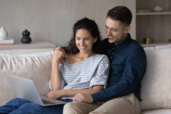 Happy couple using laptop together, relaxing on couch — Stock Photo, Image