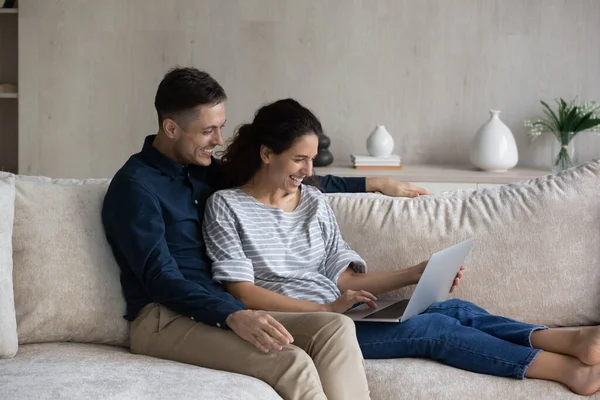 Счастливая влюбленная пара с ноутбуком, отдыхая на диване вместе — стоковое фото