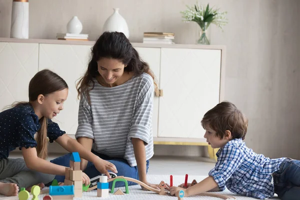 Lächelnde liebevolle Mutter und Kinder beim Spielen mit Holzspielzeug — Stockfoto