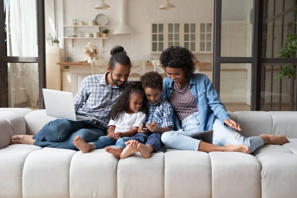 Szczęśliwy młody Afroamerykańska rodzina za pomocą różnych gadżetów. — Zdjęcie stockowe