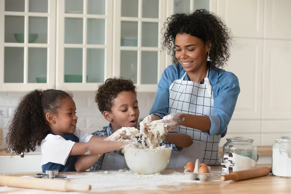 Glückliche kleine afrikanische Kinder lernen Kochen mit Mama. — Stockfoto