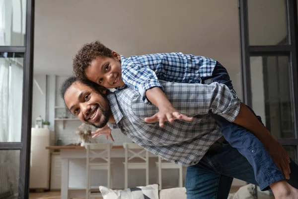 Souriant père afro-américain tenant sur le dos riant petit fils. — Photo