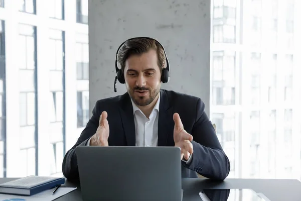 Gemotiveerde zakenman in hoofdtelefoon met microfoon spreekt op video gesprek — Stockfoto