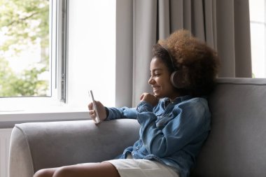 Telsiz kulaklıklı, müzik dinleyen mutlu siyah genç kız.