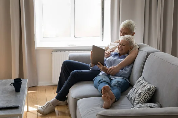 Glad senior gift par vilar på bekväm soffa tillsammans — Stockfoto