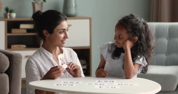 Улыбающаяся индийская мама проверяет свои дочери знания в умножении — стоковое видео