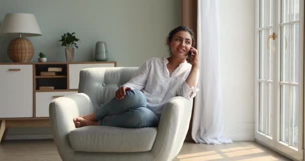 Mujer india linda relajarse sentarse en el sillón hablando en el teléfono inteligente — Vídeos de Stock