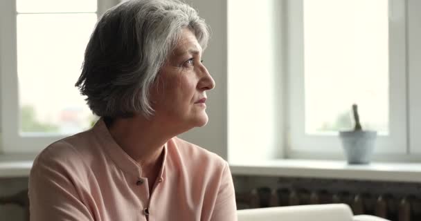 Mujer mayor suspira, mirando a la distancia sintiéndose sola y abandonada — Vídeo de stock