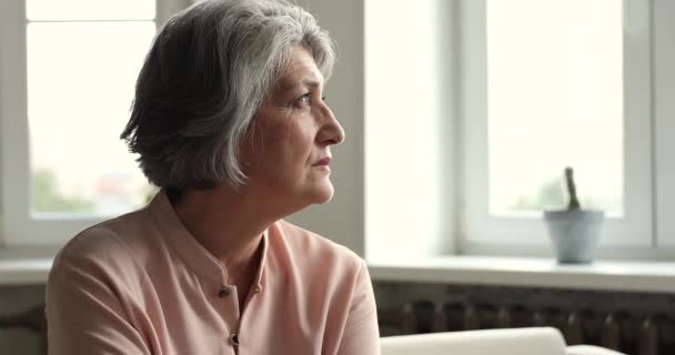 Mujer mayor suspira, mirando a la distancia sintiéndose sola y abandonada — Vídeos de Stock