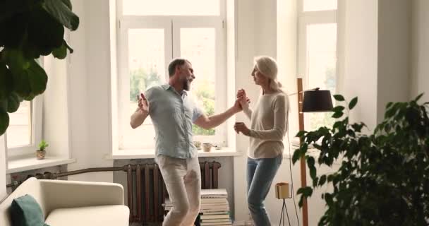 Atractiva pareja mayor escuchando música favorita bailando en el interior — Vídeo de stock