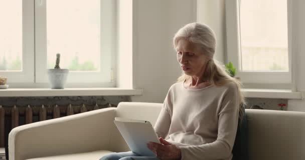 Старша жінка тримає цифровий планшет, пошукові послуги, купує товари — стокове відео