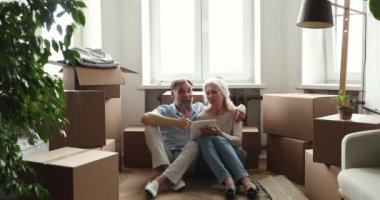 Yaşlı çift dijital tablet kullanıyor. Eşyalarının olduğu kutuların yanına otur.