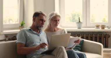 Olgun eşler kanepede oturur, belgeleri öğrenir, kağıtları düzenler.