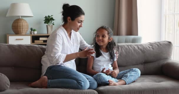 Індійська мама розмовляє з дочкою, сидячи вдома на дивані. — стокове відео