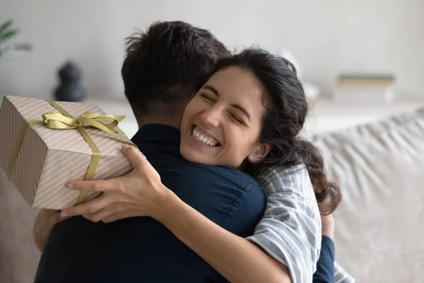 Grateful happy young woman holding festive wrap, hugging beloved husband — Stock Photo, Image
