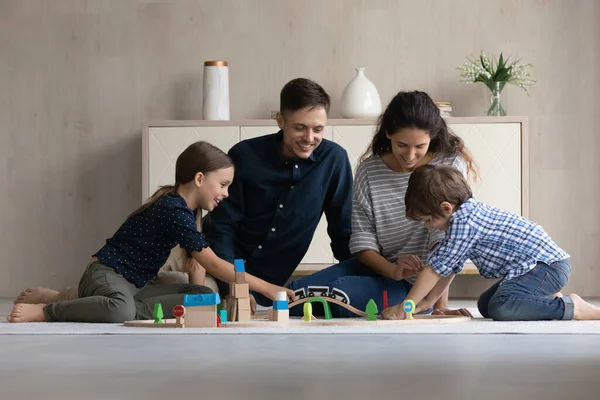 Felices padres cariñosos y dos niños jugando juegos en el suelo —  Fotos de Stock
