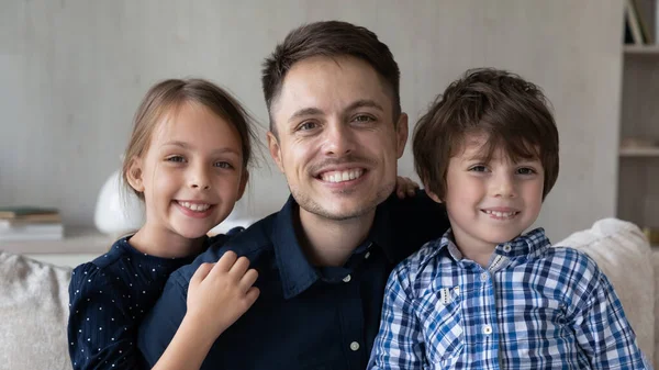 Feliz pai e dois filhos sentados no sofá em casa — Fotografia de Stock