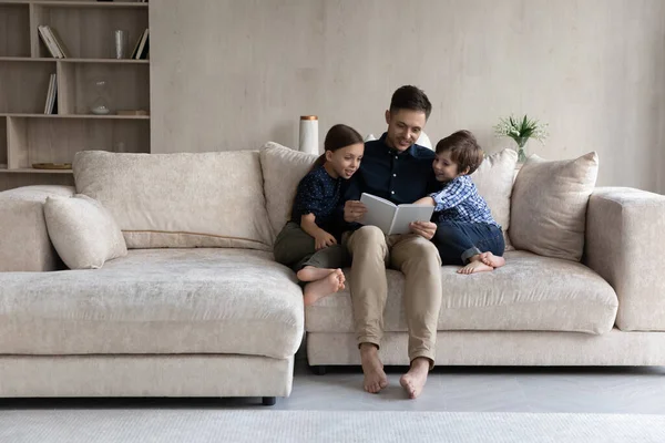 Gelukkig liefhebbende vader lezen boek aan kleine zoon en dochter — Stockfoto