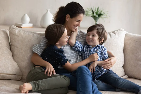 Gelukkig mam knuffelen kleine zoon en dochter met liefde — Stockfoto