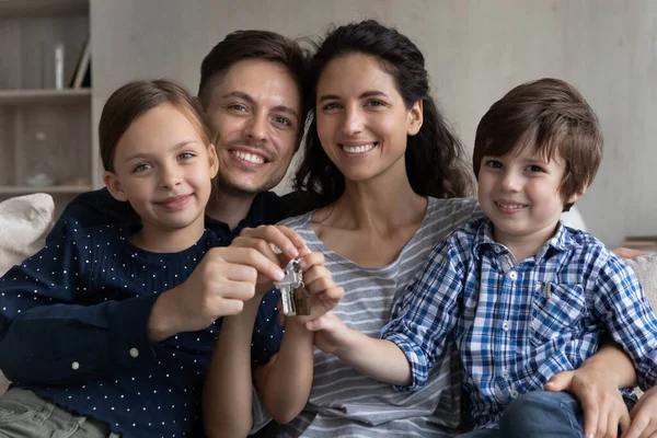 Couple heureux et deux enfants tenant les clés de la nouvelle maison — Photo