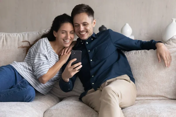 Joyeux jeune couple joyeux regardant contenu multimédia drôle sur smartphone — Photo