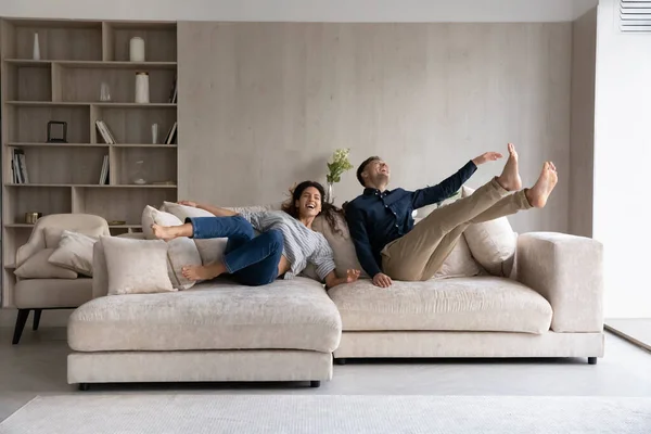 Małżonkowie nowych właścicieli domów spadających na dużą miękką kanapę — Zdjęcie stockowe