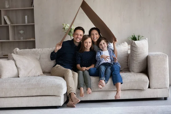 Gelukkige ouders en twee schattige kinderen met kartonnen dak — Stockfoto