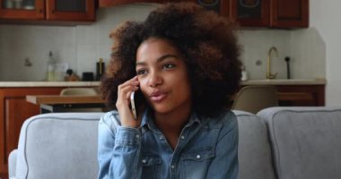 Yakından Afrikalı genç bir kız. Kanepeye oturur, akıllı telefondan boşboğazlık eder.