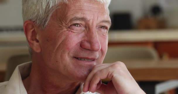 Homem mais velho sentar sorriso interior olha para o lado se sentir feliz, close-up — Vídeo de Stock