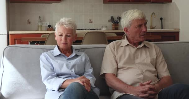 Smutný starší pár sedět na pohovce odděleně po hádce — Stock video