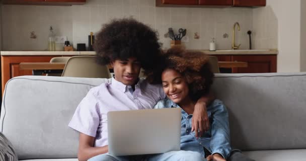 Dizüstü bilgisayara bakan Afrikalı genç çift haberleri okurken mutlu oluyor. — Stok video