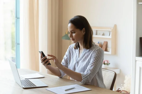 Feliz joven bonita mujer usando el teléfono celular, distraído del trabajo portátil. — Foto de Stock