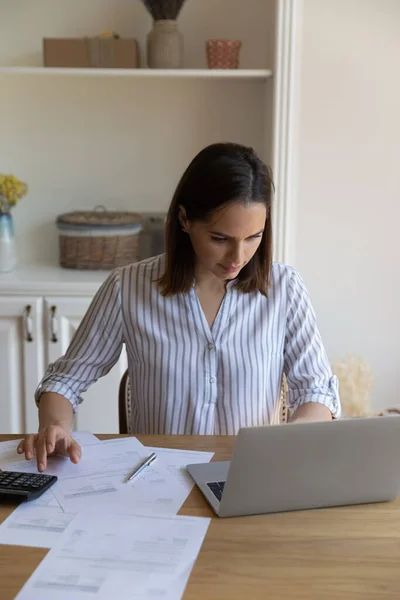 Концентрированная молодая женщина занимается финансовой бумажной работой дома. — стоковое фото
