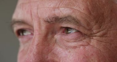 Yakından kırpılmış yüz görüntüsü ciddi olgun bir adam mesafeye bakıyor.