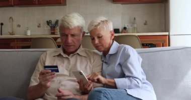Olgun çift akıllı telefon ve banka kartı kullanarak online alışverişin tadını çıkarıyor