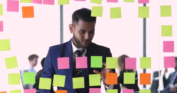 Joven haciendo la visualización del proyecto pegando papeles en la pared de vidrio — Vídeos de Stock