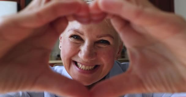 Закройте счастливую пожилую женщину с символом сердца — стоковое видео