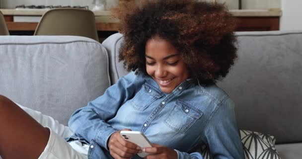 Menina adolescente africana bonito usando telefone inteligente em casa — Vídeo de Stock