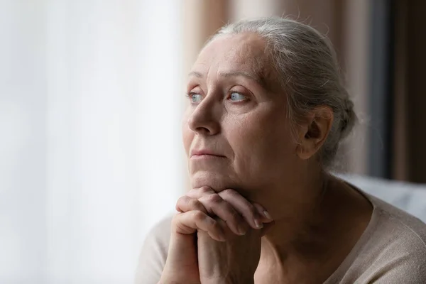 Ragionevole annoiato più vecchio anni '70 donna guardando la finestra — Foto Stock