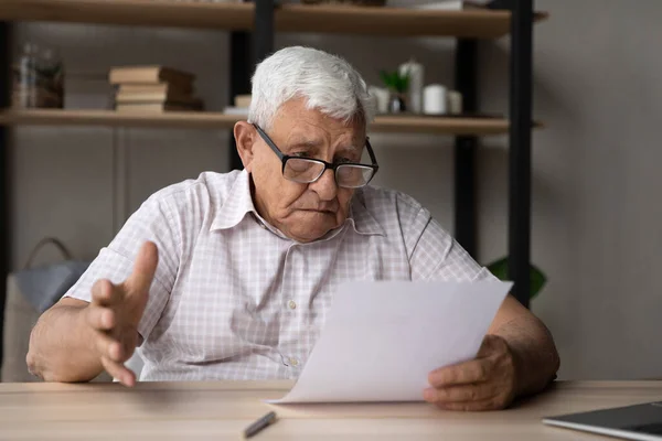 Запутавшийся пожилой мужчина 80-х годов в очках, читающий документ — стоковое фото
