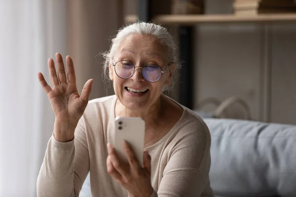 Счастливый пожилой пользователь смартфона женщина машет рукой Привет на экране — стоковое фото