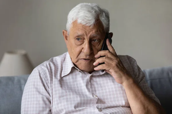 Серьезный обеспокоенный дедушка разговаривает по мобильному телефону — стоковое фото