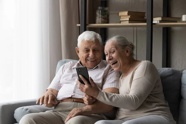 Feliz animado casal mais velho usando smartphone — Fotografia de Stock