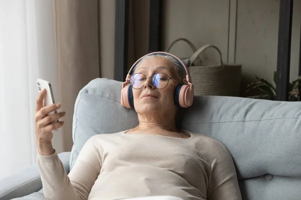 Calme dame âgée dans les écouteurs sans fil écouter de la musique relaxante — Photo