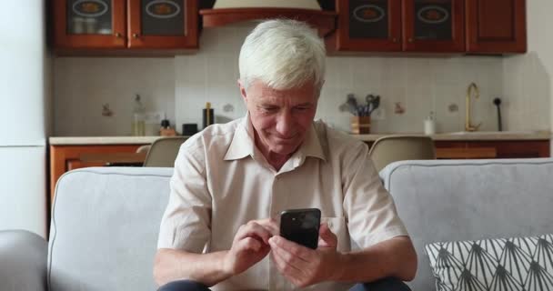 Glimlachende oudere man met smartphone genieten van nieuwe mobiele applicatie — Stockvideo