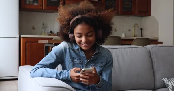 Adolescente africaine tient téléphone portable écoute de la musique à travers des écouteurs — Video